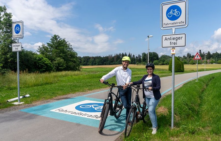 Fahrradstrasse Schmalegg-Bastin-Bogenrieder 2 Menschen mit Fahrrädern vor beschilderter und markierter Fahrradstraße