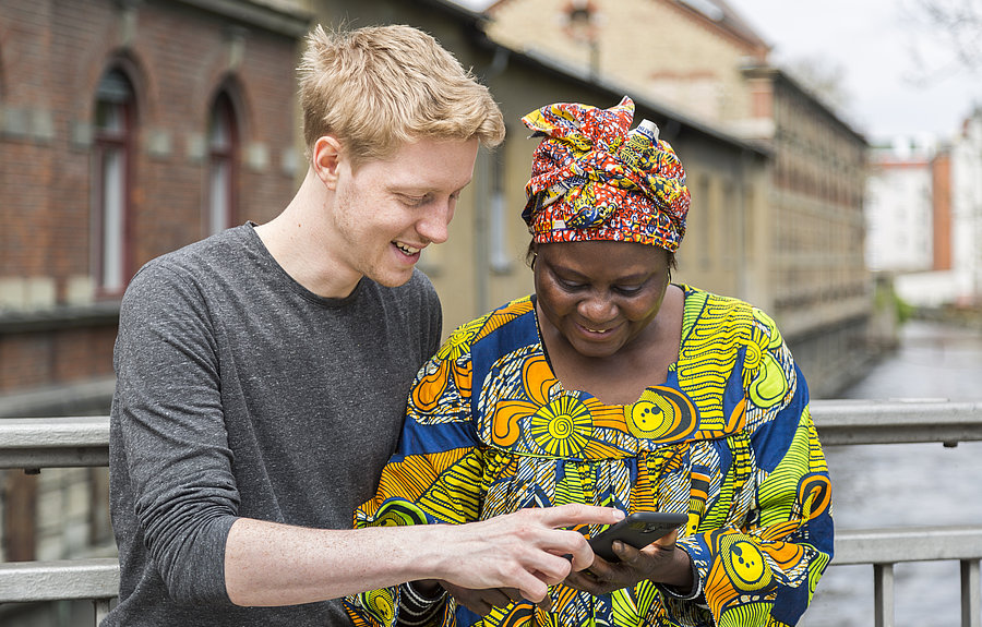 Integreat-Textbausteine Mann zeigt Frau Mobilitätsinformationen am Handy